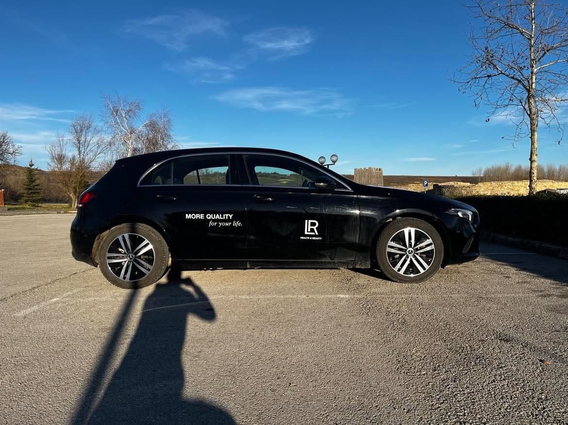 Бял Mercedes с логото на LR в профил под синьо небе